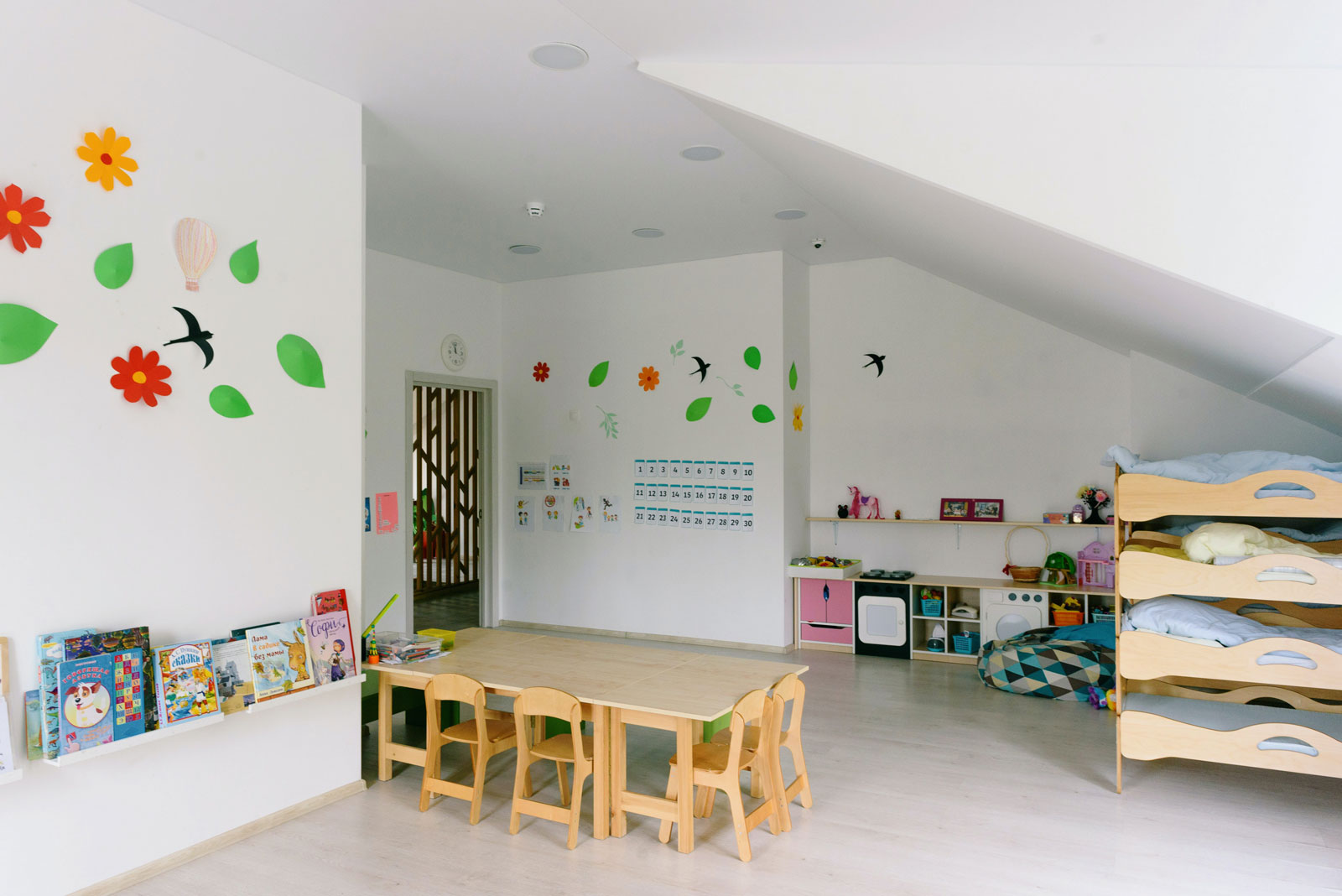 Raum in einem Kindergarten mit kleinen Betten und Stuehlen.