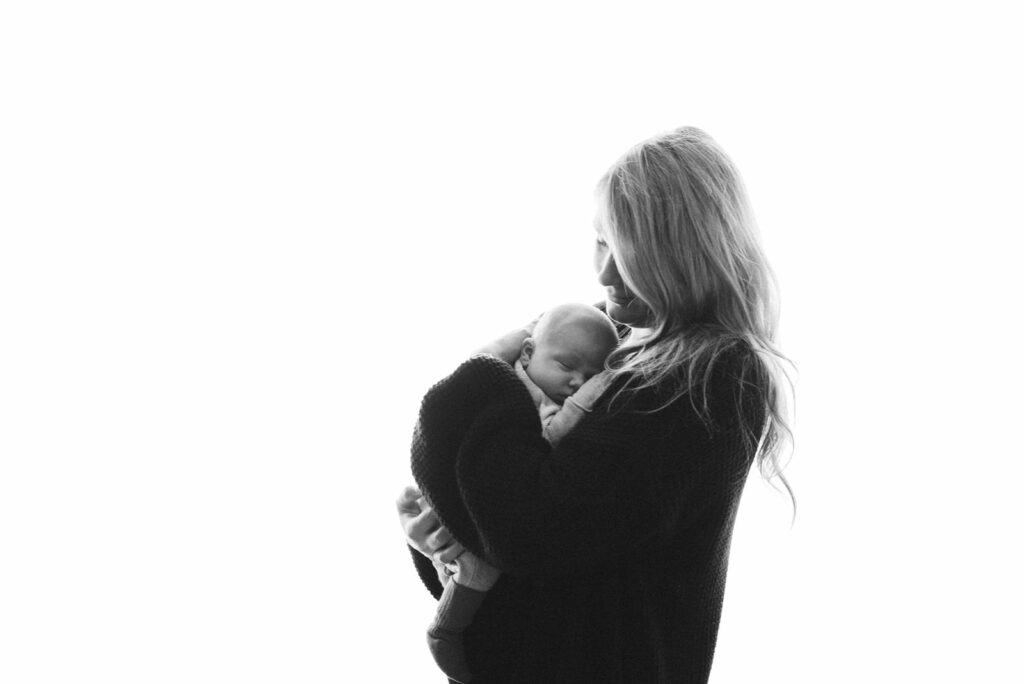 Fotografie einer Mutter mit ihrem Baby vor weißem strahlendem Hintergrund.