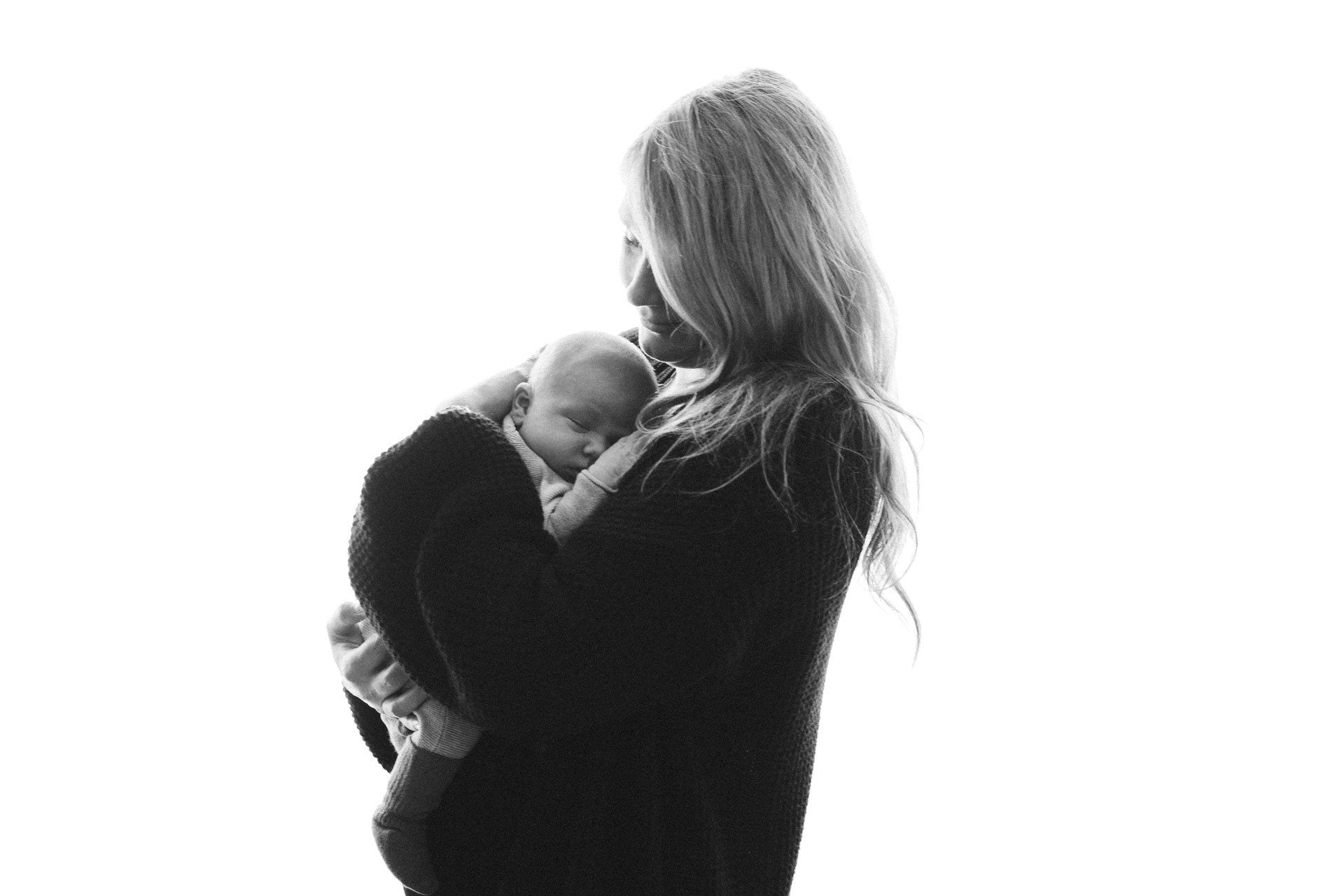 Fotografie einer Mutter mit ihrem Baby vor weißem strahlendem Hintergrund.