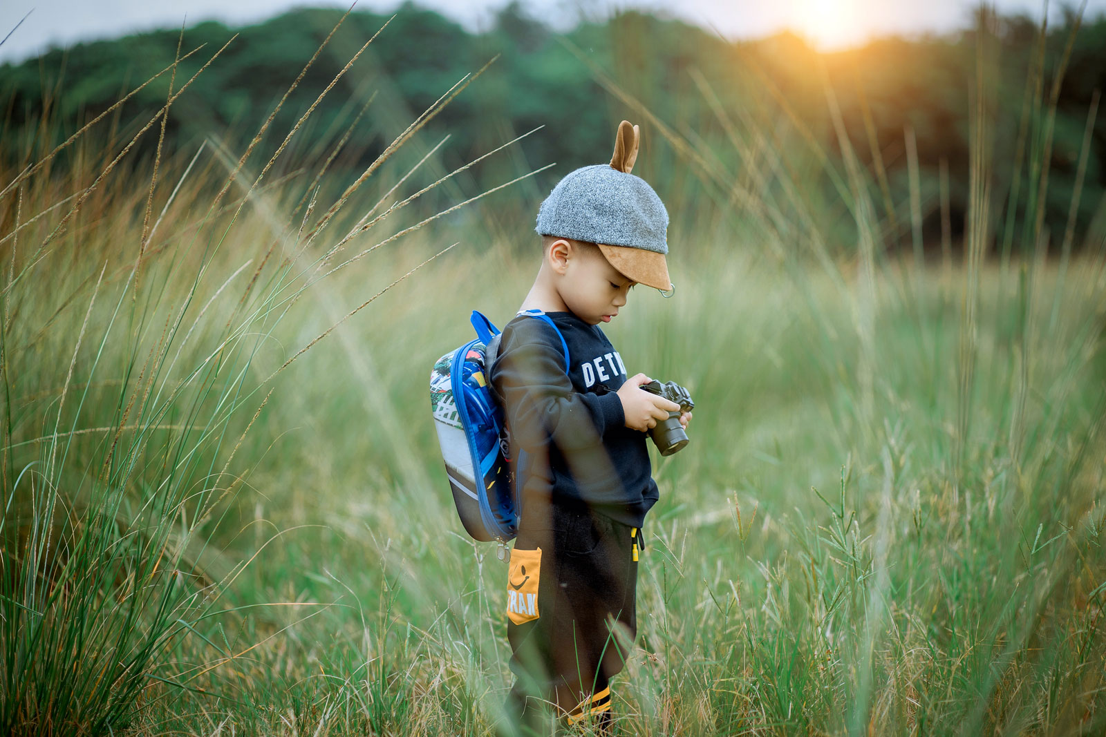 Bis zum Mond und wieder zurueck: Kinderfotografie in Duesseldorf fuer Kitas Junge auf einem Feld betrachtet ein Bild auf einer Kamera.