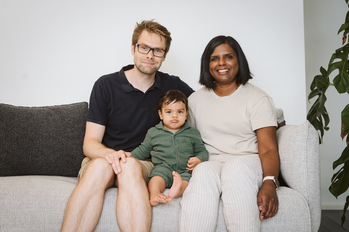 Familie auf moderner Couch im Fotostudio Düsseldorf, Baby mit lustigem Gesichtsausdruck.