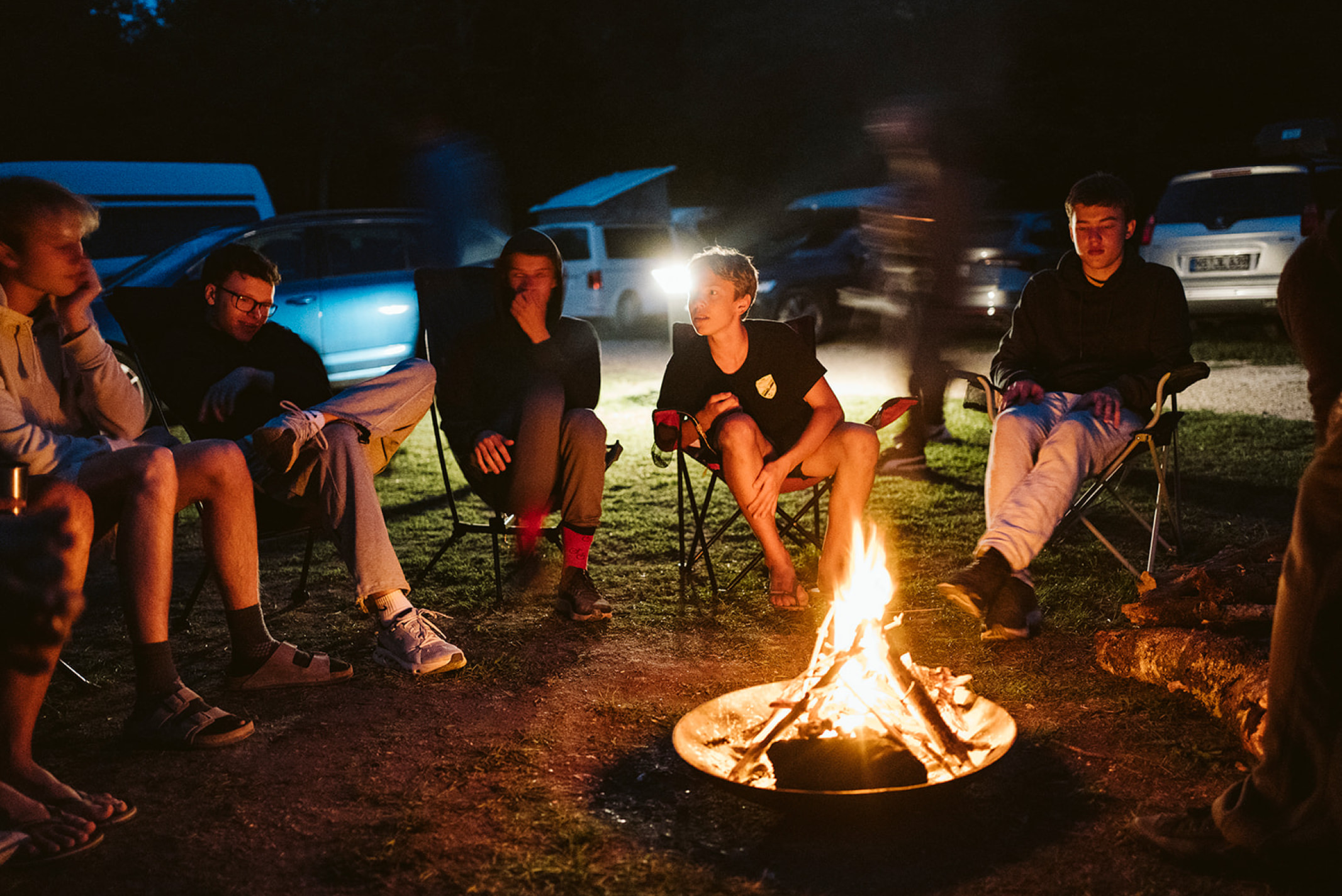 Jugendliche von ParkourOne um ein Lagerfeuer in Fontainebleau.