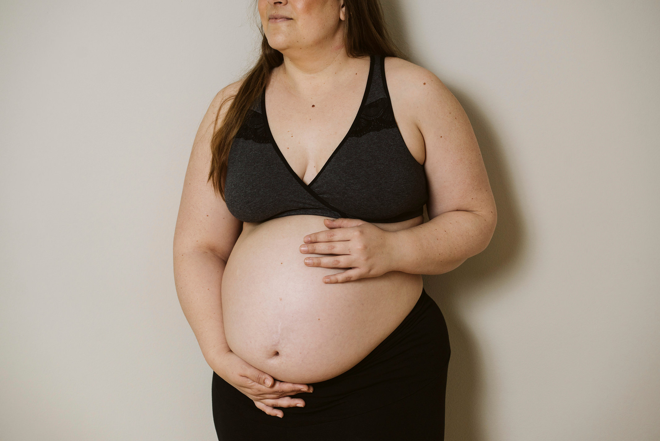 Frau mit Babybauch und nur die untere Hälfte des Gesichts ist am oberen Bildrand zu sehen.