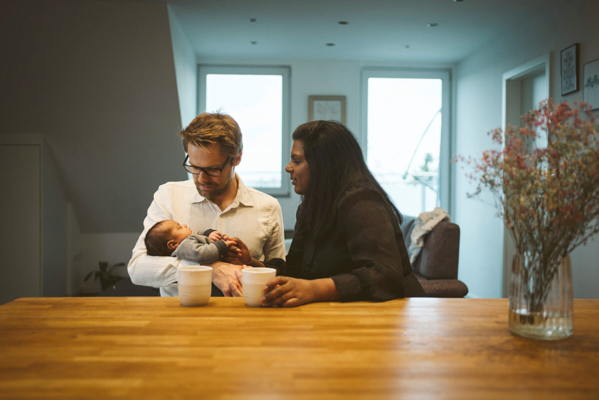 Eltern mit ihrem neugeborenen Baby bei einer Newborn-Homestory zu Hause