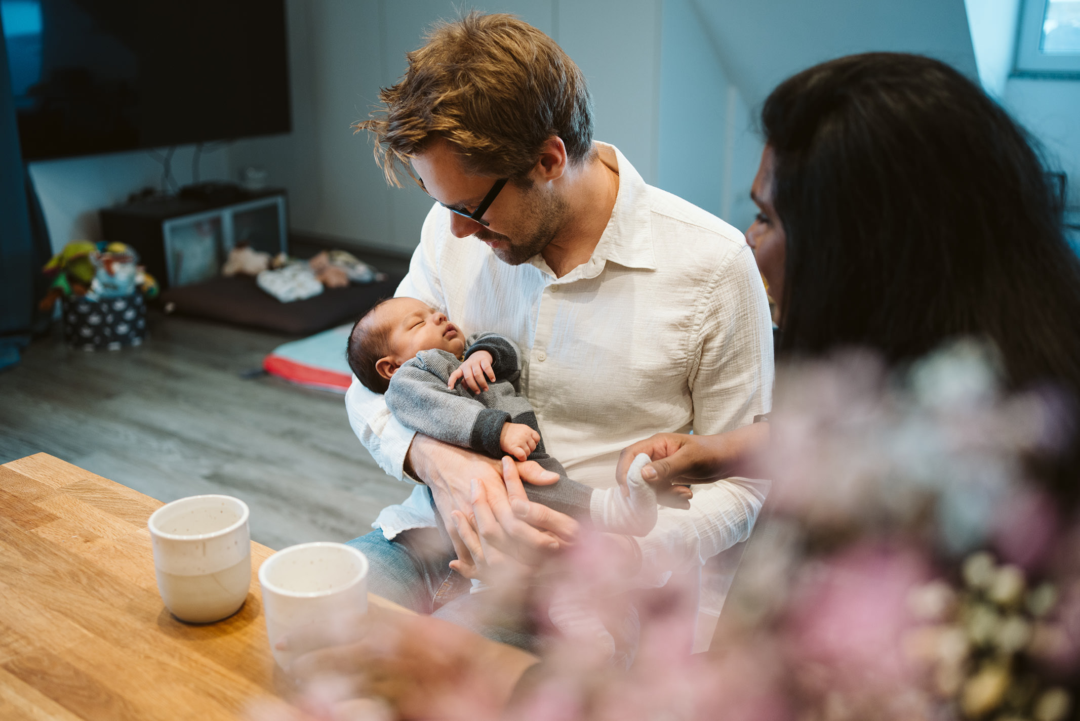 Vater mit Baby am Esstisch bei einer natürlichen Newborn-Homestory