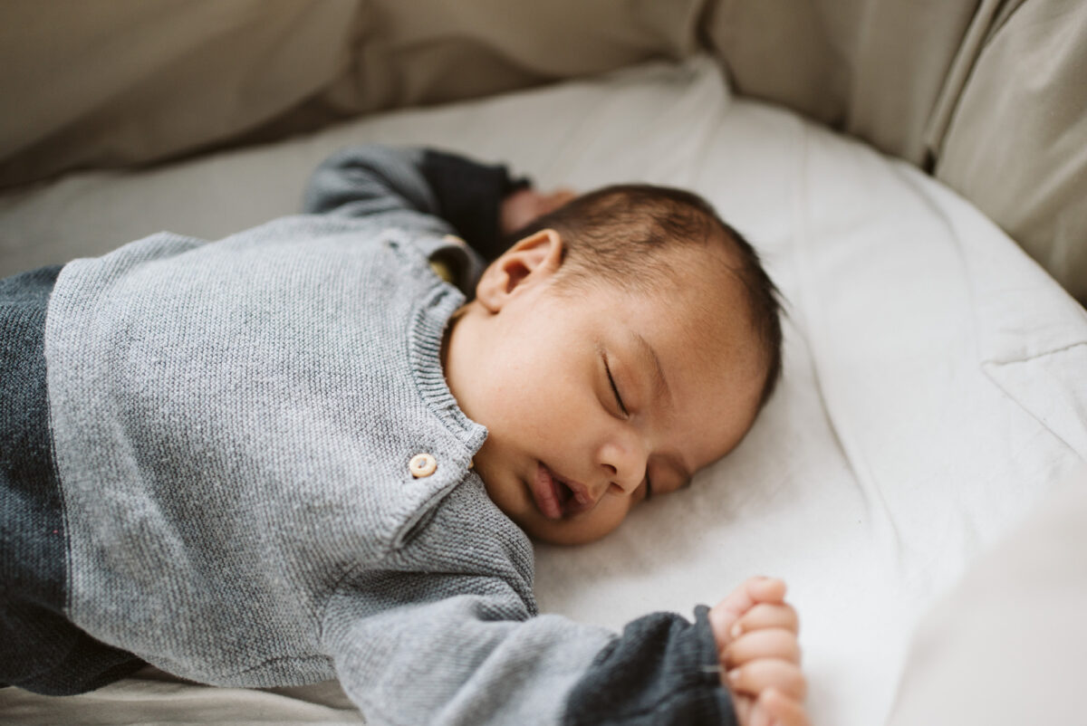 Neugeborenes Baby schläft auf einer weißen Decke im Bett