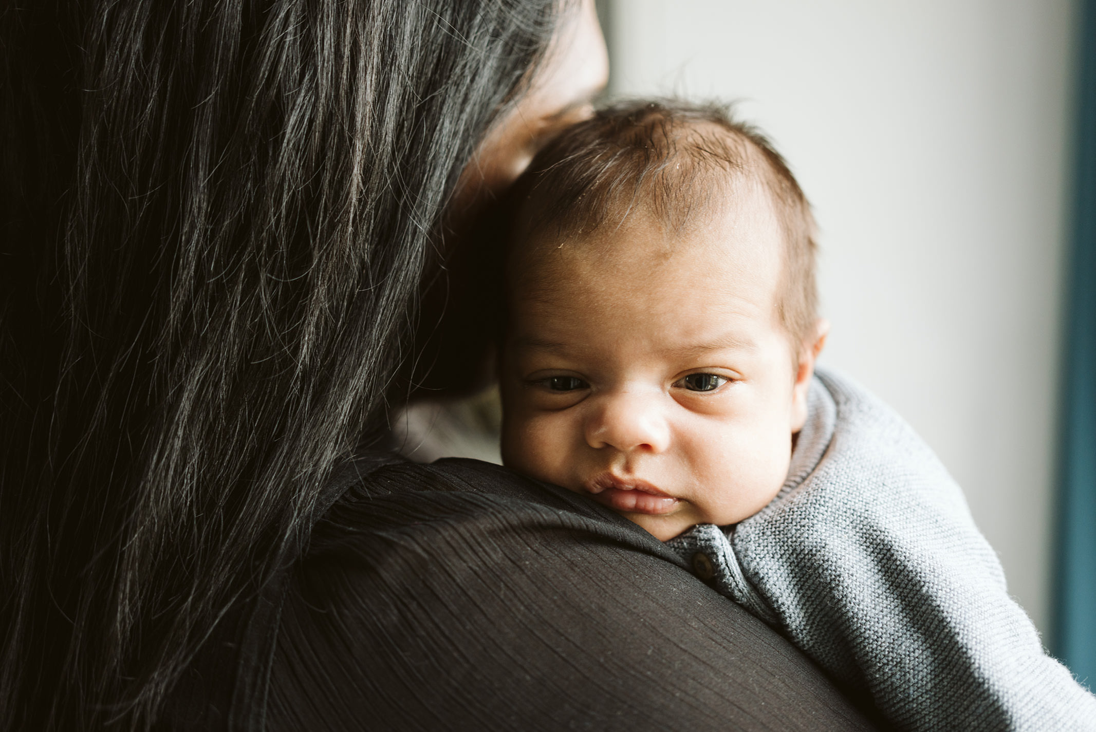 Neugeborenes Baby liegt geborgen auf der Schulter seiner Mutter